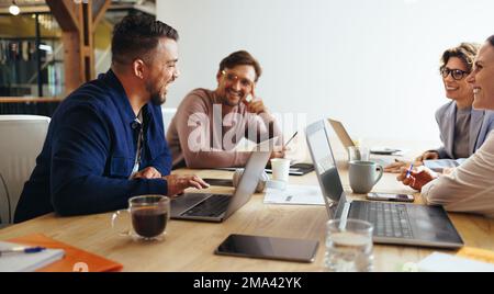 Advertising professionals having a meeting in a boardroom. Group of creative professionals having a discussion in an office. Happy business team worki Stock Photo