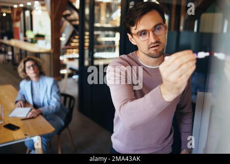 business man presenting his ideas to his team in a meeting. Male professional leading a project in an office. Team of professionals working together i Stock Photo