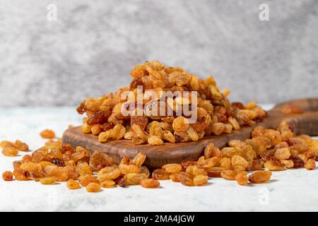 Raisins on stone background. Organic pile of yellow raisins on a wooden serving board. Dried healthy nuts. close up Stock Photo