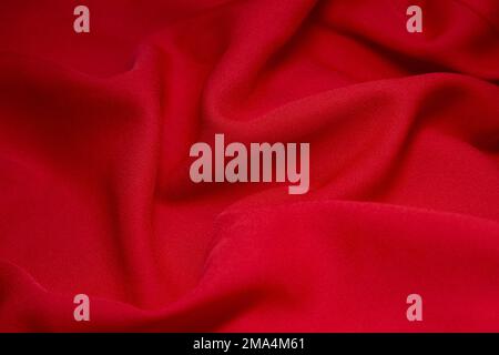 Red fabric background. Red cloth waves background texture. Red fabric cloth textile material. Stock Photo