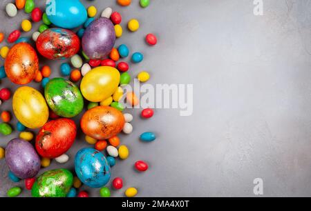 Colorful Easter eggs and chocolate Easter sweets  on grey background. Top view with copy space. Festive Easter concept. Stock Photo