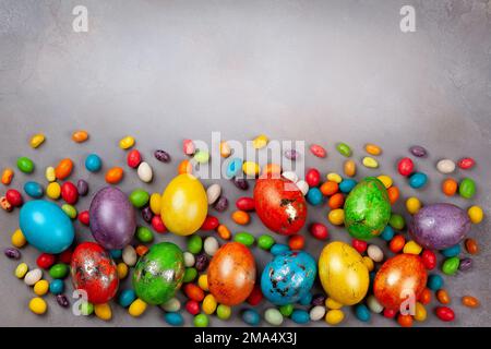 Colorful Easter eggs and chocolate Easter sweets  on grey background. Top view with copy space. Festive Easter concept. Stock Photo