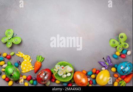 Colorful Easter eggs,chocolate Easter sweets, bunny and nest with chicks  on grey background. Top view with copy space. Festive Easter concept. Stock Photo