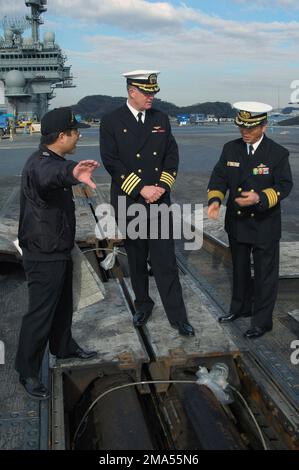 041221-N-6490U-002. [Complete] Scene Caption: US Navy (USN) Captain (CAPT) Thomas Parker (center), Commanding Officer (CO), USS KITTY HAWK (CV 63), accompanies CAPT Akira Aoki (right), CO, Japan Defense Ship (JDS) SHIRANE, on a tour of the KITTY HAWK's flight deck. The HAWK and SHIRANE recently participated in a traditional Japanese gift exchange, promoting cultural relations and friendship between the United States and Japanese Navies. The HAWK received two 'Kadomatsu,' which are traditional Japanese decorations of pine trees and bamboo, placed at the gates of houses and businesses during the Stock Photo