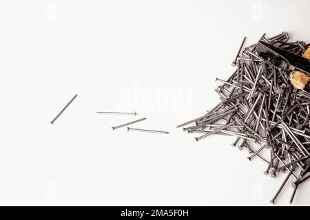 Group of a carpenter's nails stacked on a white work table with an old wooden hammer on them. Stock Photo