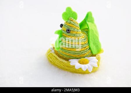 chicken figurine made of green twine sitting on a nest. Easter symbols on the snow are a symbol of the spring holiday Stock Photo