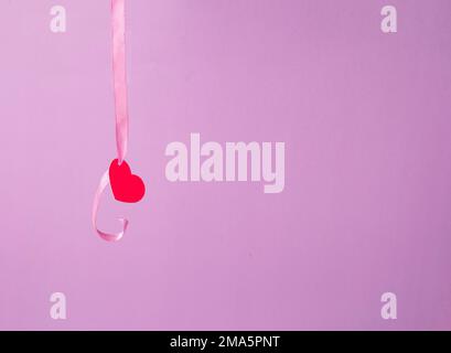 Flying cleansing moisturizing hyaluronic serum acid and red paper hearts on pink background. Valentine's Day. Symbol of love. Copy space. Stock Photo