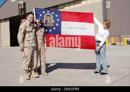 050207-F-4132J-035. [Complete] Scene Caption: Newlyweds TECH. SGT. Charles Bittle (left), a life support technician, and TECH. SGT. Susan Palmer (second from left), a load master, pose with their Georgia State Flag with'Just Married'written on it prior to a deployment for Southwest Asia at Savannah International Airport, Savannah, Ga., on Feb. 7, 2005. The couple was married at the Mighty 8th Air Force Museum chapel nine days before deploying. They are both members of the 165th Airlift Wing, Georgia Air National Guard. (U.S. Air Force PHOTO by STAFF SGT. Shaleata Johnson) (Released)The 165th A Stock Photo