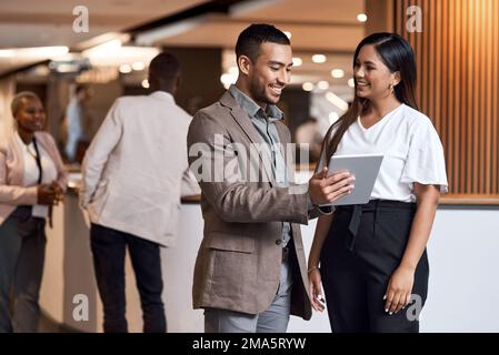 Meet with influential people and make your presence known. a young businessman and businesswoman using a digital tablet at a conference. Stock Photo