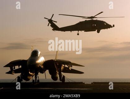 A US Navy (USN) HH-60H Seahawk, Helicopter Anti-Submarine Squadron Seven (HS-7), Dusty Dogs, Naval Air Station North Island (NASNI), approaches the flightdeck during flight operations aboard the Nimitz Class Aircraft Carrier USS HARRY S. TRUMAN (CVN 75). In the foreground sits a USN F-14B Tomcat fighter, Fighter Squadron 32 (VF-32), Swordsmen, NAS Oceana, Virginia (VA), part of Carrier Air Wing 3 (CVW-3) embarked aboard the TRUMAN to provide close air support (CAS) and conduct intelligence, surveillance and reconnaissance over Iraq during Operation IRAQI FREEDOM. The TRUMAN Carrier Strike Grou Stock Photo