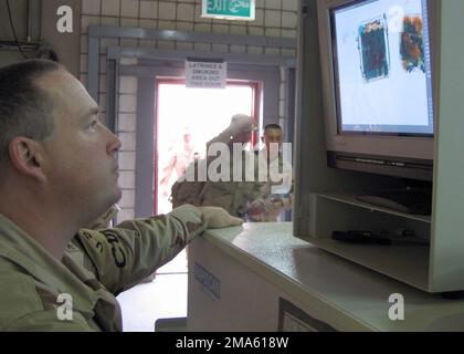 050412-6592B-003. [Complete] Scene Caption: US Navy (USN) Aviation Ordnanceman Second Class (AO2) Malvin Howe, uses the newly installed color X-ray machine to inspect personal baggage of American Soldiers heading home from Operation IRAQI FREEDOM through Camp Doha, Kuwait. AO2 Howe, a Navy Reservist assigned to Naval Expeditionary Logistics Support Force (NAVELSF), Forward (FWD) OSCAR, Bravo (B) Company (CO), on Camp Doha, Kuwait. NAVELSF, FWD OSCAR performs the US Customs and US Department of Agriculture (USDA) mission for the US Army (USA) in Kuwait and Iraq. This is the first time the US Na Stock Photo