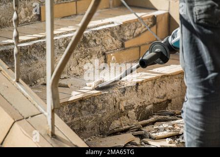 Man removes tiles from a stair using a hammer drill Stock Photo