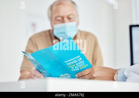 Making sure my patients know everything before being vaccinated. a senior man sitting with his doctor and looking at a leaflet during a consult in the Stock Photo