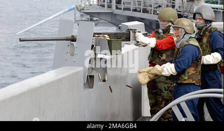 US Navy (USN) AIRMAN (AN) Melissa Wabon fires an M2.50 caliber machine gun while Torpedoman's Mate SEAMAN (TPSN) Manny DeJesus and GUNNER's Mate Third Class (GM3) Peter Lussier, observe during a live-fire exercise aboard the Nimitz Class: Aircraft Carrier, USS RONALD REAGAN (CVN 76), while underway in the Pacific Ocean conducting Tailored Ship's Training Availability (TSTA). Base: USS Ronald Reagan (CVN 76) Country: Pacific Ocean (POC) Stock Photo