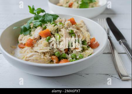 Brown rice with chicken and vegetables. on a plate with knife and fork on white background. healthy meal for fitness, diet or healthy eating Stock Photo
