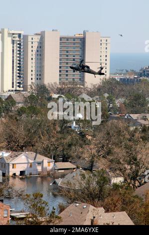 050904-A-0000D-063. A Texas Army National Guard (TXARNG) UH-60 Black Hawk (Blackhawk) helicopter flies over a flooded New Orleans, Louisiana (LA), while dropping sandbags on a breached levee, during relief operations. (A3593) Stock Photo