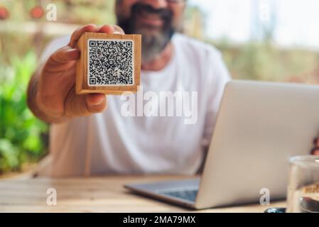 Man inbackground showing qr code menu at the cafe. Digital online modern people lifestyle and job. Laptop computer. Cliente use qr code to see the men Stock Photo