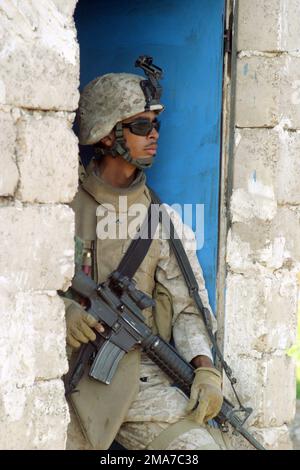 US Marine Corps (USMC) Lance Corporal (LCPL) Hector Figueroa, 2nd Squad (SQD), 1ST Platoon (PLT), Fox Company (F CO), 2nd Battalion (BN), 2nd Marines, stands in a doorway while the home is searched for weapons during Operation Trifecta under Operation IRAQI FREEDOM. LCPL Figueroa is armed with a KAC 5.56 mm Modular Weapon System (MWS) SOPMOD (Special Operation Peculiar Modification) M4 rifle. Base: Zaidon State: Al Anbar Country: Iraq (IRQ) Stock Photo