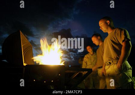 051120-F-7234P-143. [Complete] Scene Caption: US Navy (USN) PETTY Officer Third Class (PO3) Jessica Young (left), PO3 Arthur Perry, and PETTY Officer Second Class (PO2) Ron Brown (right) stand over a makeshift grill during downtime at a US military camp in Harar, Ethiopia. USN Construction Battalion (SEABEE) with Naval Mobile Construction Battalion 3 (NMCB 3), Port Hueneme, California (CA), dug three wells and are staging to drill several hand-pump wells, to provide thousands of Ethiopians and their livestock with potable water. US Army (USA) Soldiers from 1ST Battalion (BN), 294th Infantry Di Stock Photo