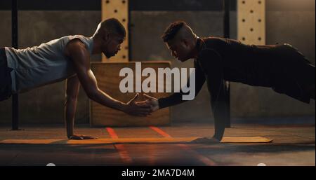 Getting into action to get stronger. two young men doing pushups together in a gym. Stock Photo