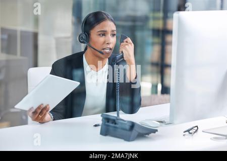 Ive got better things to do than this. an attractive young businesswoman sitting alone and feeling stressed while wearing a headset and using a Stock Photo