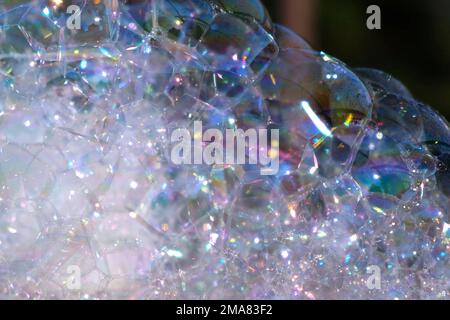 A Lot of Soap Bubbles are Bursting. Bubbles Surface on Nature Background. Texture of Big Foam. Creative concept of dreaming, happiness and magic. Abst Stock Photo