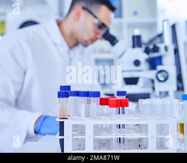 Time to get these vials filled. vials in a lab with an unrecognizable male scientist working in the background. Stock Photo