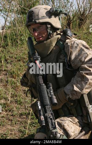 060317-M-0374B-003. [Complete] Scene Caption: On 17 March 2006, a Marine with 3rd Squad, 2nd Platoon, Echo Company, 2nd Battalion, 6th Marines, Regimental Combat Team 5, kneels during a pause while patrolling along the Euphrates River in Fallujah, Iraq during Operation California Dreaming. They are in search of weapon caches and any items that could be used to make improvised explosive devices (IED's). RCT-5 is deployed with I MEF in support of Operation Freedom in the Anbar Province of Iraq (MNF-W) to develop the Iraqi Security Forces, facilitate the development of official rule of law throug Stock Photo