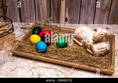 Easter lamb made of cake with colorful Easter eggs on straw, still life Stock Photo