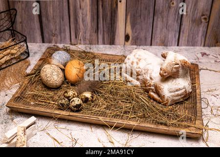 Easter lamb made of cake with colorful Easter eggs on straw, still life Stock Photo