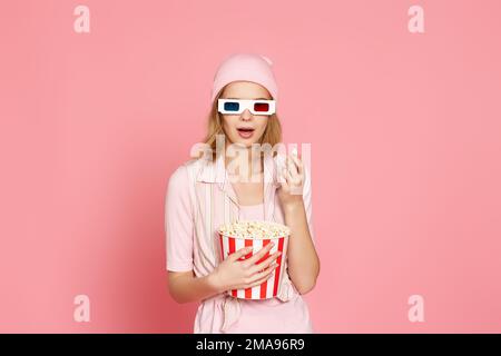 woman watching movie film, holding bucket of popcorn Stock Photo