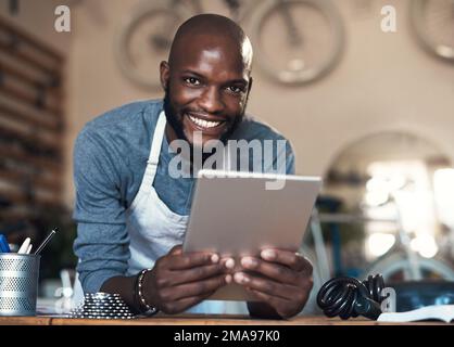 As dedicated as white on rice. Portrait of a young man using a digital tablet at work. Stock Photo