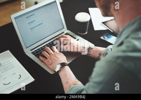 Checking for new job posts. a young businessman using a laptop in an office at work. Stock Photo