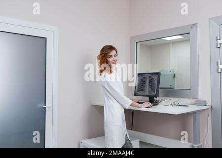 Radiological office of the hospital. Remote control of the X-ray fluorography apparatus. A female radiologist sets up an X-ray machine for radiography Stock Photo