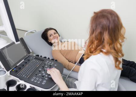 a female doctor performs ultrasound diagnostics of the intestine, abdominal cavity, right lobe, liver, bile ducts, gallbladder. Soft tissue examinatio Stock Photo