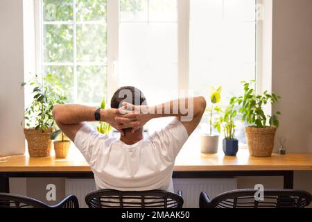 Young personal development coach answering the client by email by a laptop while having break in a coffee shop. Hipster guy searching the information Stock Photo