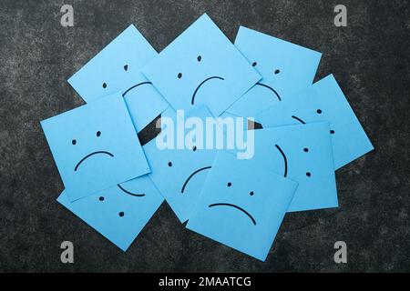 Blue sticky notes blank with drawing sad face on black background with copy space ready for your message. Blue Monday and mental health concept idea. Stock Photo