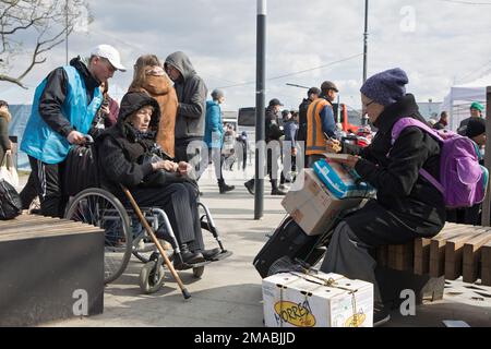 12.04.2022, Ukraine, Oblast, Lviv - Ukrainian war refugees gather in front of the main railway station in Lviv. An old woman with luggage is sitting o Stock Photo