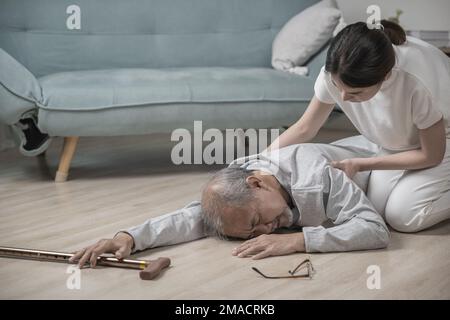 Asia young woman halping her father after falling down on floor Stock Photo