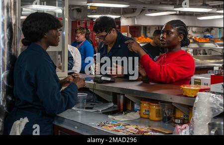 220525-N-JO823-1035 PHILIPPINE SEA (May 25, 2022) Aviation Ordnanceman 3rd Class Dora Snoh, from Columbus, Ohio places an order at the Hellcat Café with Retail Services Specialist 3rd Class Briana Orange, from Tacoma, Washington, left, aboard the U.S. Navy’s only forward-deployed aircraft carrier, USS Ronald Reagan (CVN 76). Ronald Reagan, the flagship of Carrier Strike Group 5, provides a combat-ready force that protects and defends the United States, and supports alliances, partnerships and collective maritime interests in the Indo-Pacific region. Stock Photo