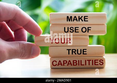 Make use of your true capabilities text on wooden blocks with hand and blurred nature background. Motivational concept Stock Photo