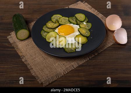 Fried egg with sliced zucchini on burlap mat and wooden table Stock Photo