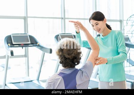 The elderly woman in teaching under the guidance of fitness Stock Photo