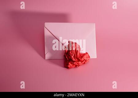 Paper heart - a crumpled sheet of paper for writing with a craft envelope. A crumpled sheet of paper in the shape of a heart on a pink background. Val Stock Photo