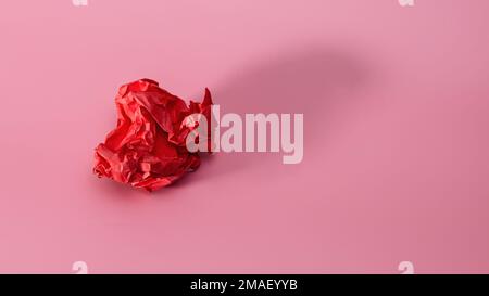 Crumpled red paper on a pink background with a trend shadow. Screwed up Craft Paper Ball. Junk paper can be recycle Stock Photo