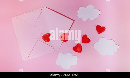 Hearts flying out of an open craft envelope. Paper clouds on a pink background. Declaration of Love on Women's Day or Mother's Day Stock Photo
