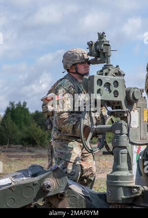 A U.S. Army Soldier assigned to the 1-119th Field Artillery Regiment, Michigan Army National Guard, looks through a scope during Summer Shield at Forward Operating Site Adazi, Latvia, May 26, 2022. Summer Shield, led by Latvian Mechanized Infantry Brigade is one of multinational training exercises in Eastern Europe that make up Defender Europe 22 exercise, led by U.S Army Europe and Africa. Defender demonstrates U.S. Army Europe and Africa’s ability to conduct large-scale ground combat operations across multiple theaters supporting NATO. Stock Photo