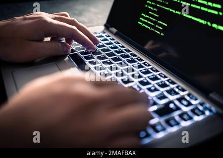 Hacker with malware software code in computer screen. Developing fraud website. Cybersecurity attack and web crime with laptop. Cyber security. Stock Photo