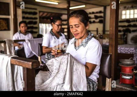 Bali - Indonesia - 10.22.2015: Elderly indonesian women applying wax on batik in a touristic atelier Stock Photo