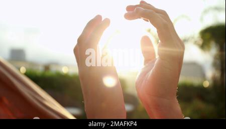 Close-up of hands joining together with sunlight flare in the background. Beautiful romantic moment between two lovers Stock Photo